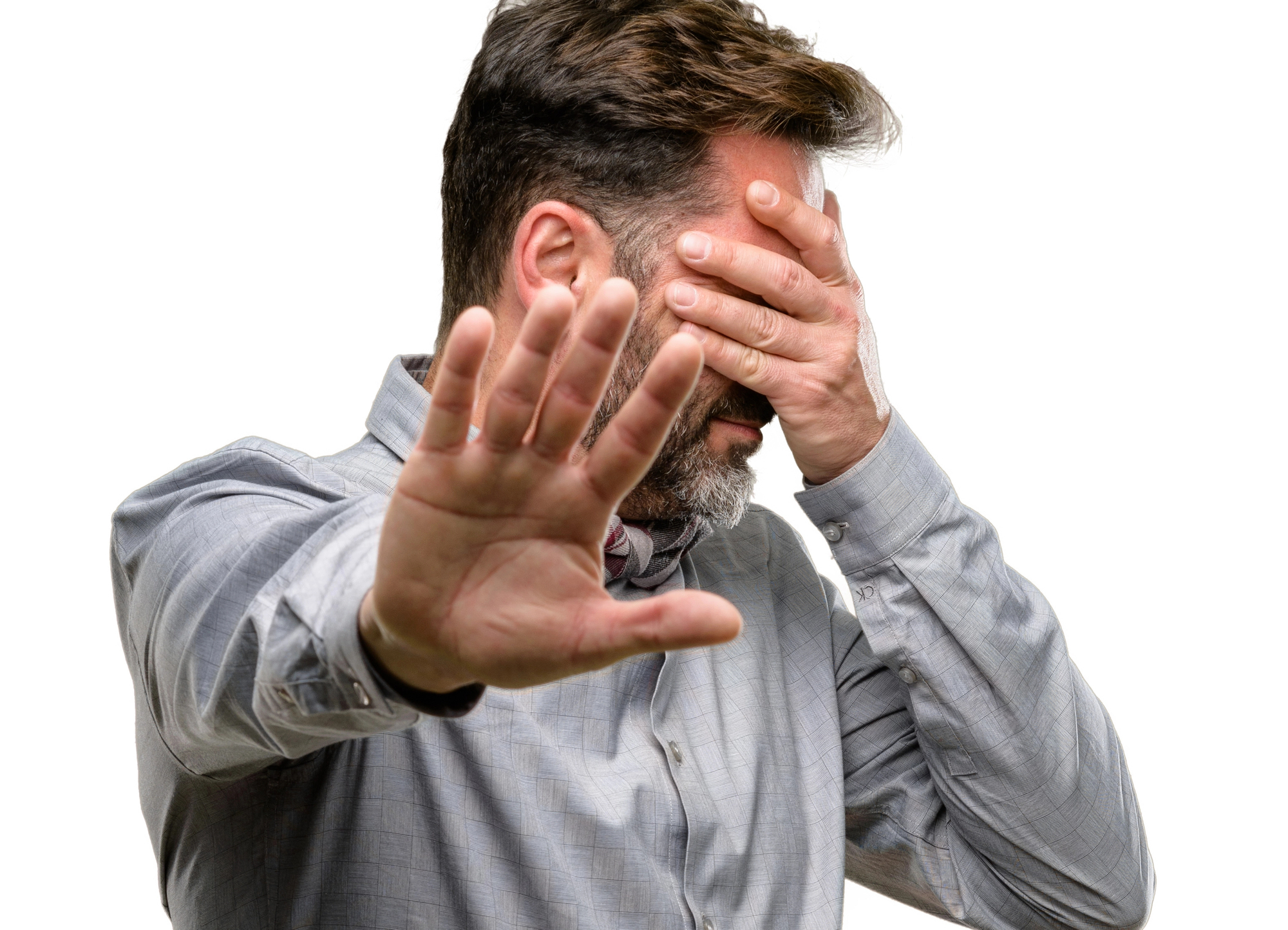 Businessman covering his face in frustration and holding his hand out to stop another person from talking