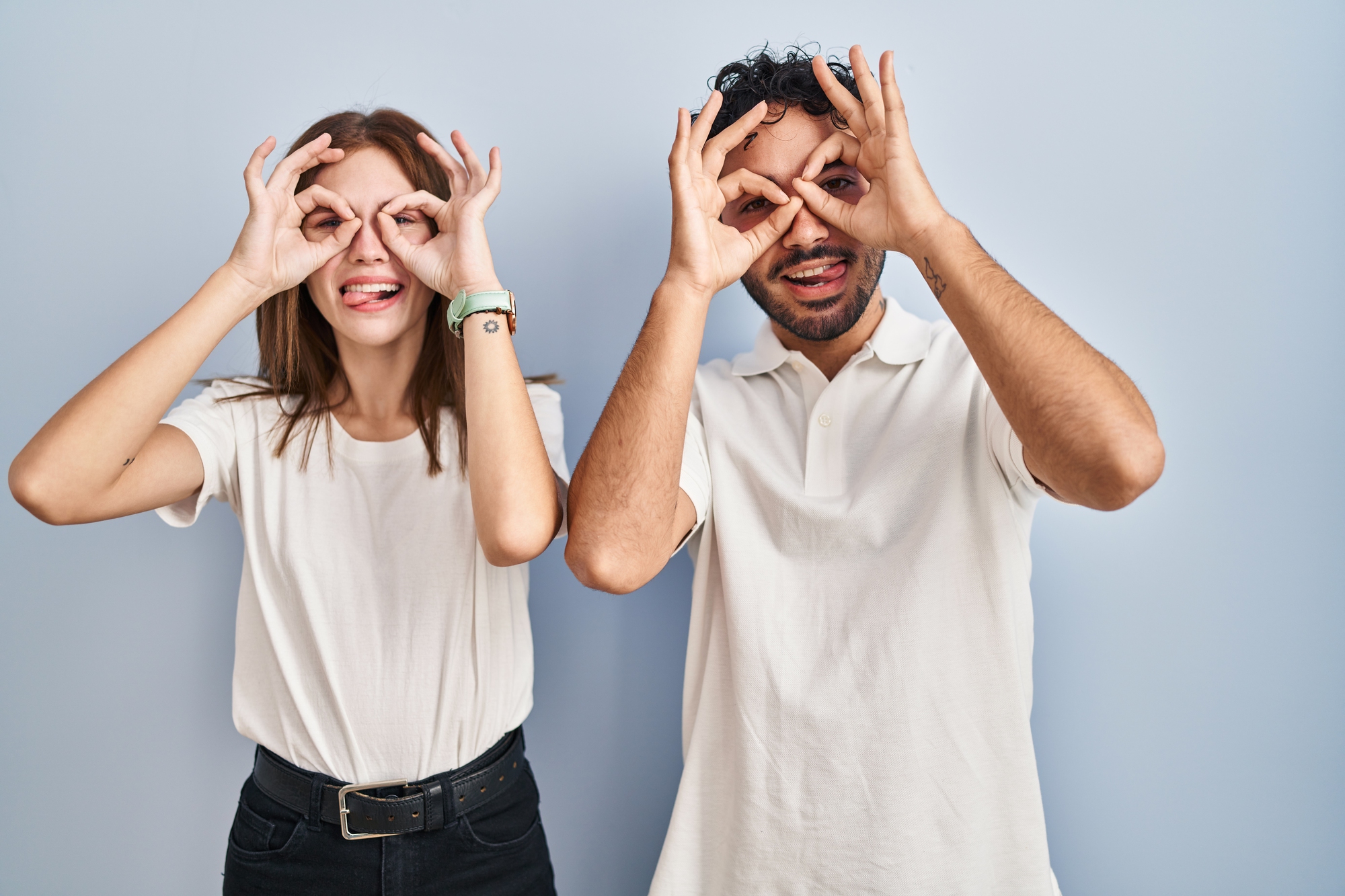 Woman and man being silly, holding hands to eyes like glasses