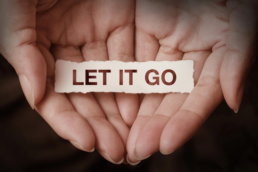 Two hands cupped, holding a papercut message: LET IT GO