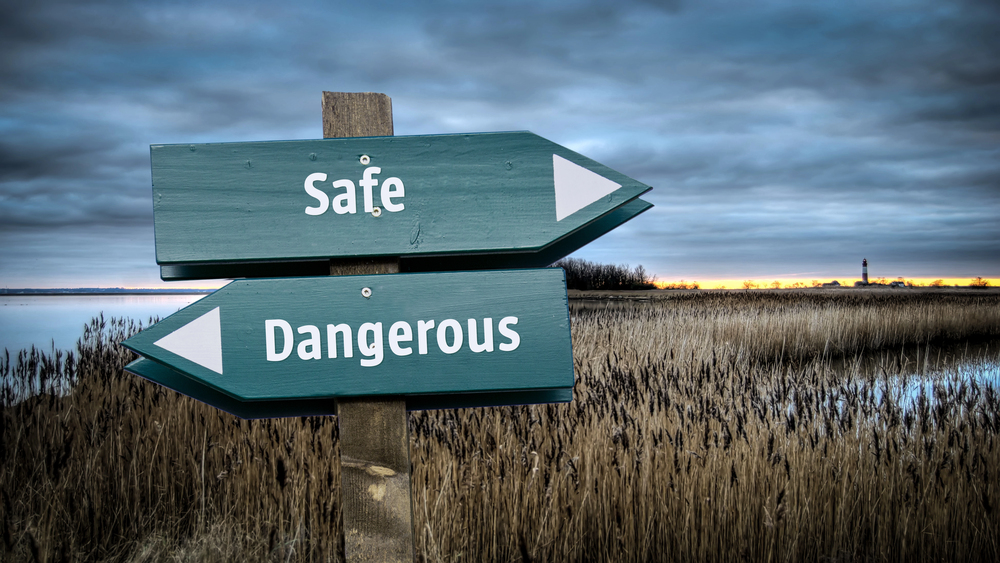 A sign in the middle of a wetland with two choices in opposite directions: safe, and dangerous