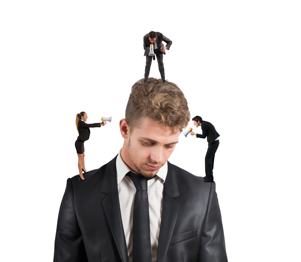 Man being yelled at by tiny coworkers with megaphones standing on his shoulders & head