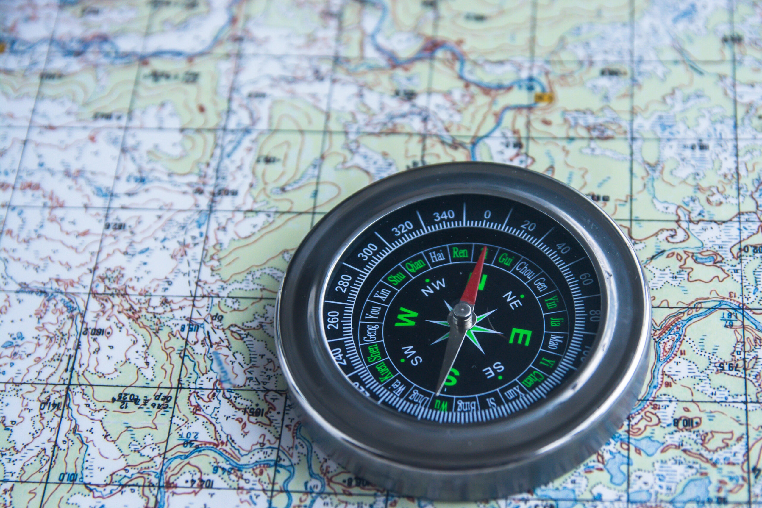Compass laying atop a topographical map